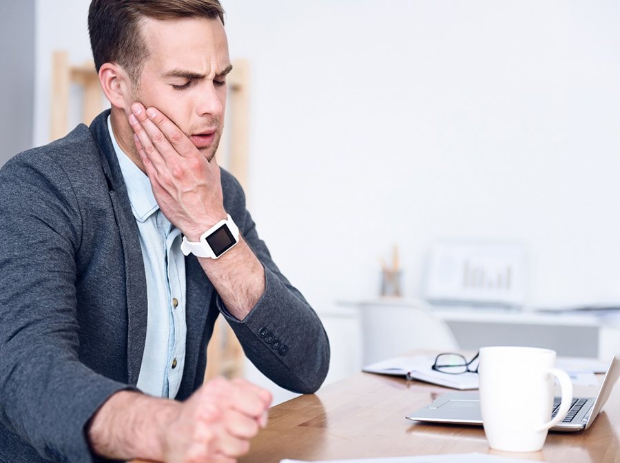 Businessman rubbing his face in concern due to tooth pain