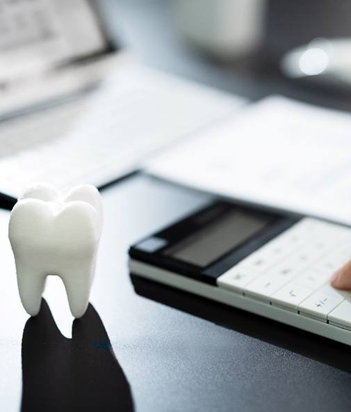 Tooth on table; person using a calculator