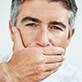 Man in need to dental implant tooth replacement covering his mouth