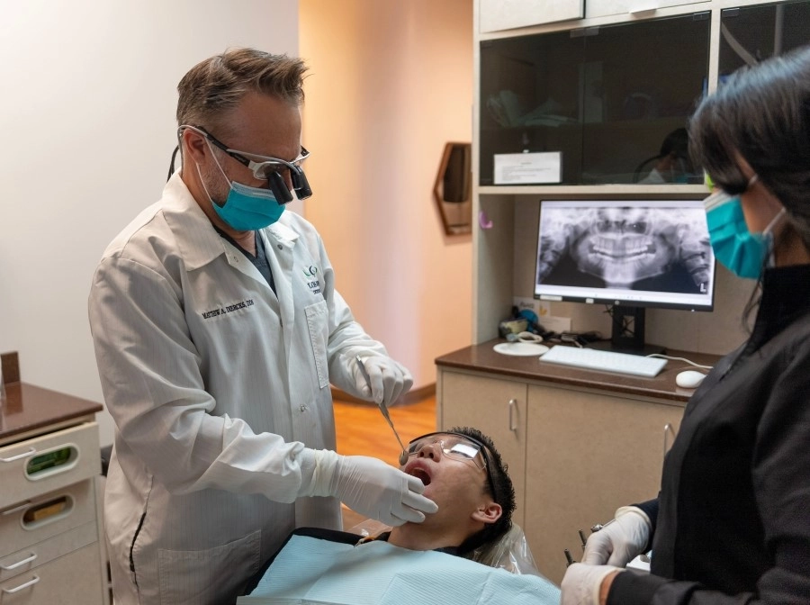 Dentist examining a patient with the assistance of a dental hygienist