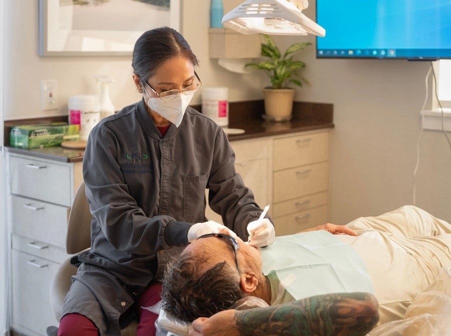 A dental assistant assisting a patient seated in the dental chair