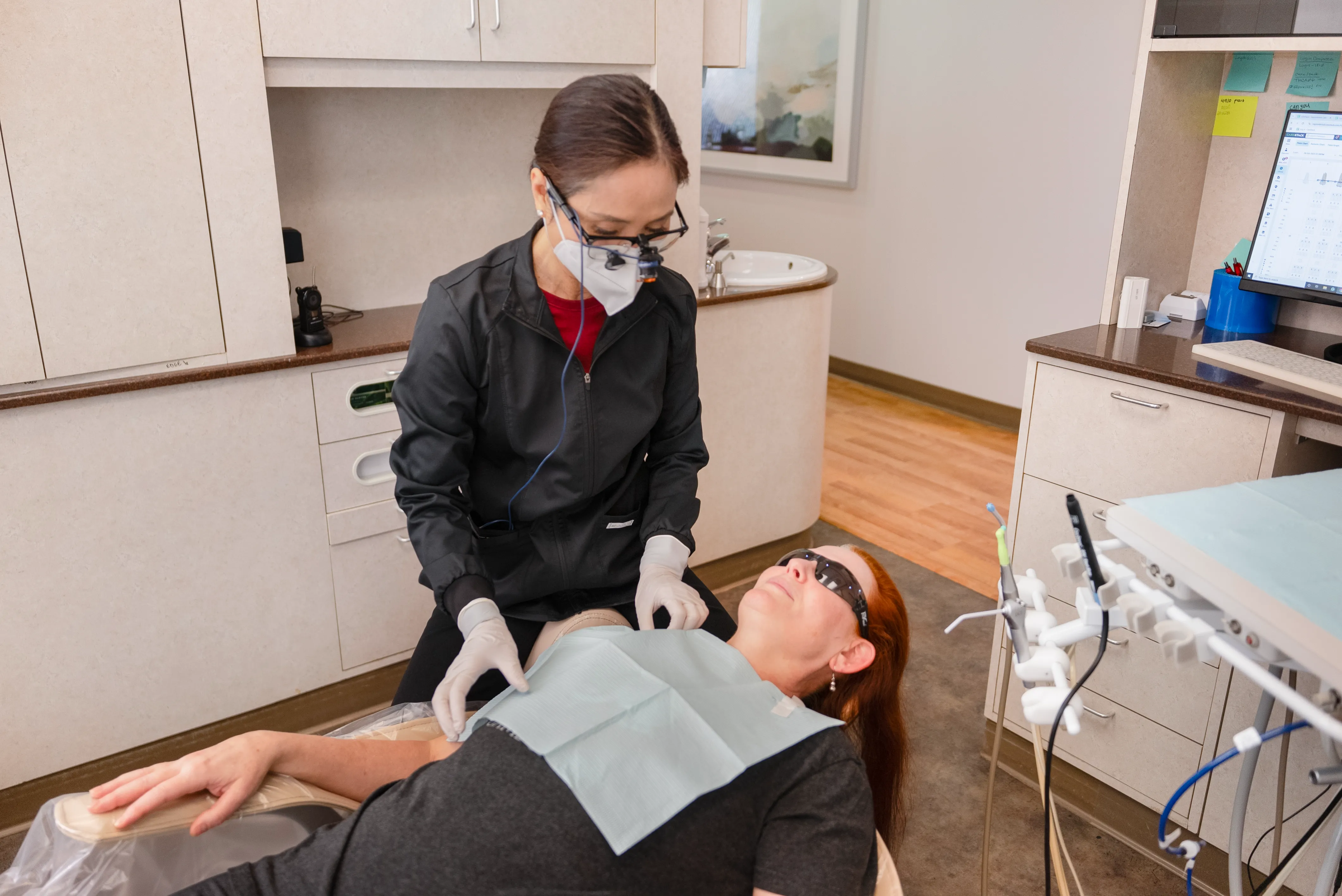 A dental assistant assisting a patient seated in the dental chair