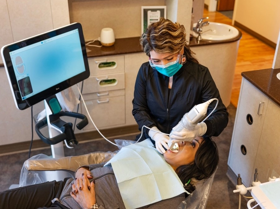 Dental assistant using an intraoral scanner to capture a 3D image of a patient's teeth, a common step in planning full-mouth reconstruction treatments.