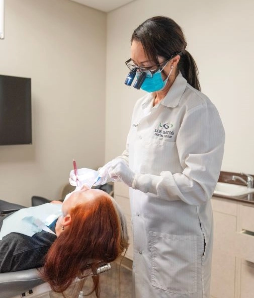 Dentist performing a procedure while the patient is reclined in the dental chair.