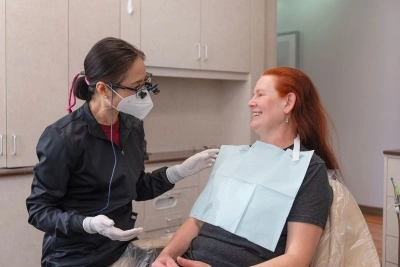 A dental hygienist conversing with a patient seated in a dental chair