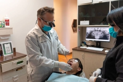 Dentist assisted dental assistant working on a patient seated in a dental chair