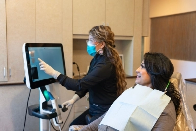 Dental assistent and patient sitting on dental chair looking on screen after a mouth scanning